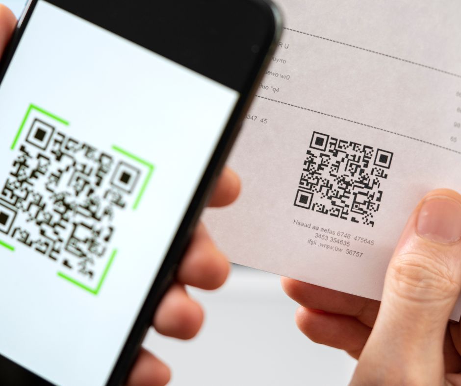 Hand hält Smartphone und scannt QR Code von einem Zettel