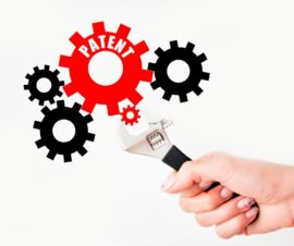 Patentrecht, Hand hält Zange, die an Zahnrad mit der Aufschrift Patent dreht